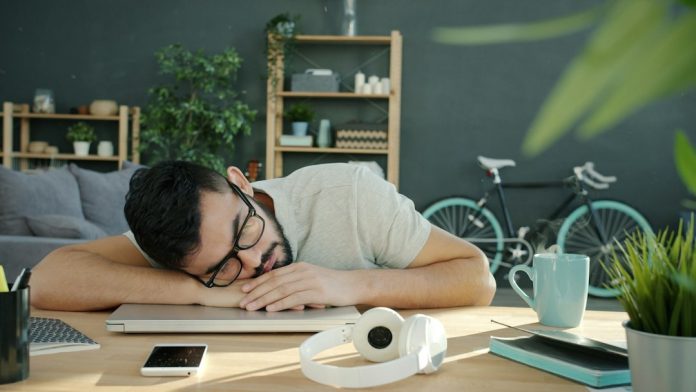 An adult resting at a desk, illustrating persistent fatigue and the need for medical evaluation.