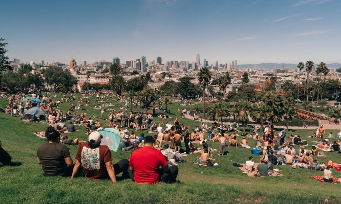 People relaxing outdoors in a city park during warm weather; photo by Kaden Taylor on Unsplash