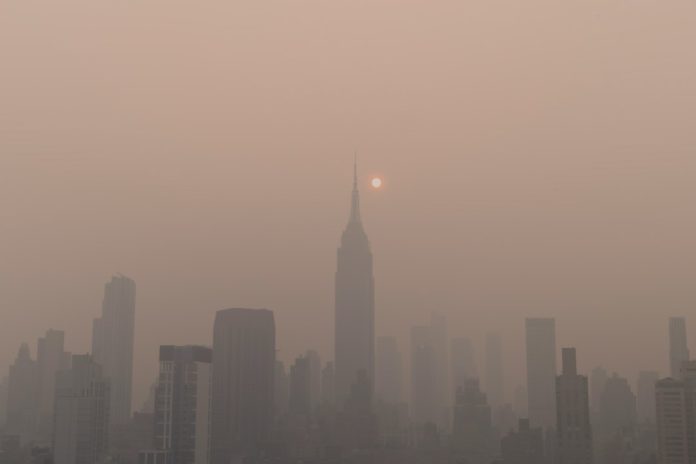 Sun glowing through haze over a city skyline, illustrating climate and public health risks