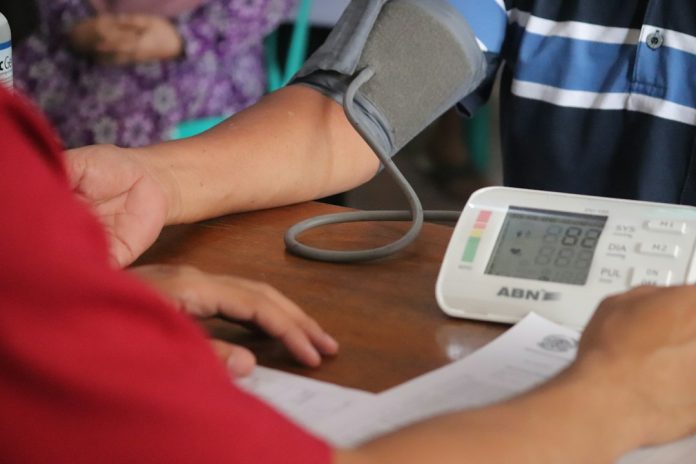 Person using a blood pressure monitor at a table