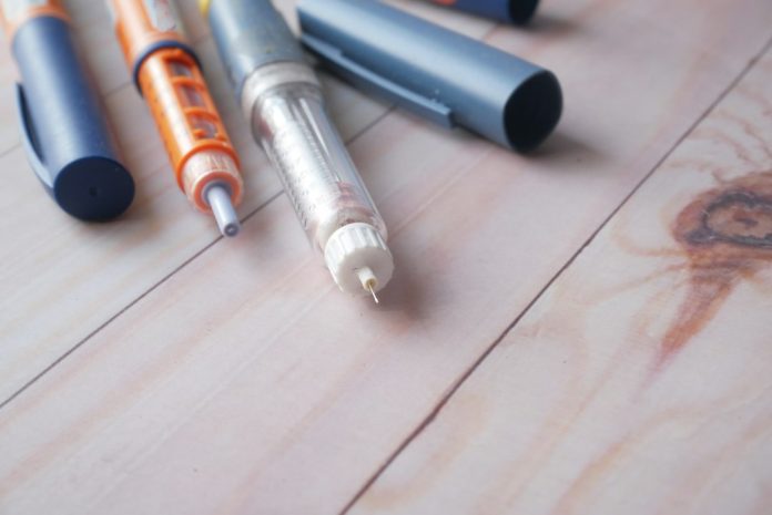 Insulin pens arranged on a wooden surface for an article about safe home sharps disposal. Photo: Towfiqu barbhuiya / Unsplash.
