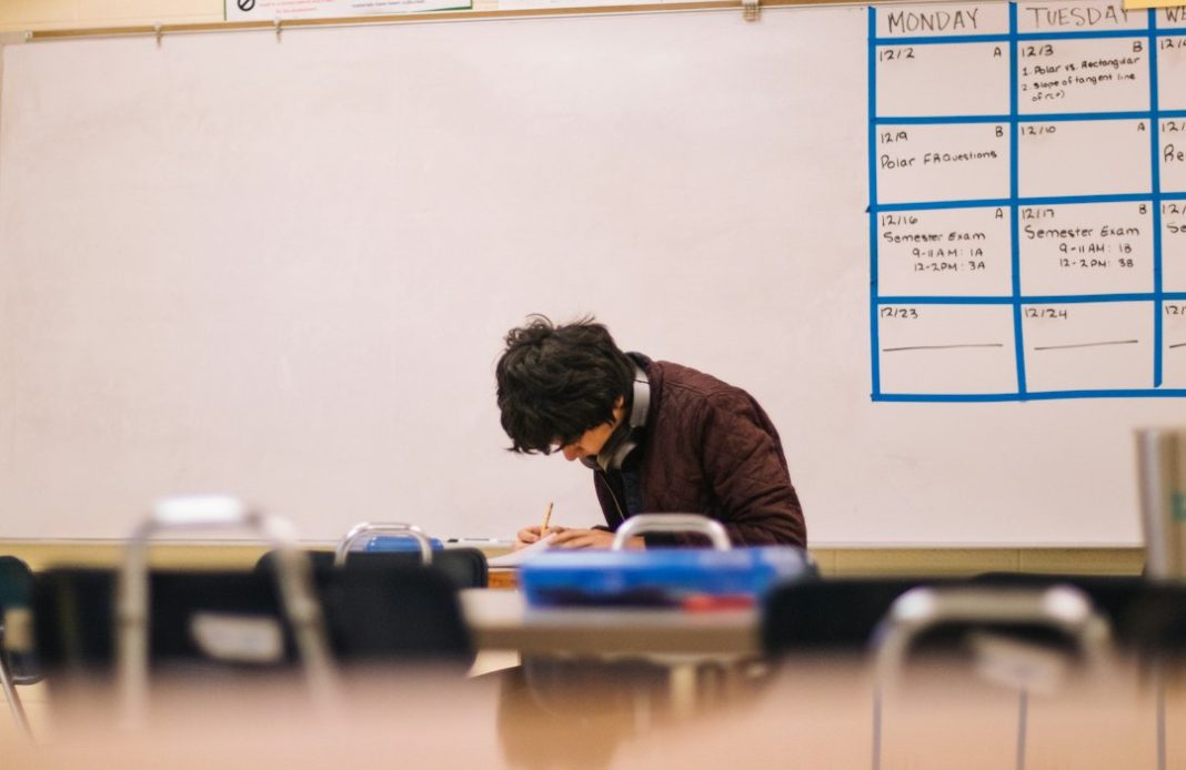 Adult learner writing at a desk in a classroom