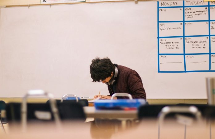 Adult learner writing at a desk in a classroom