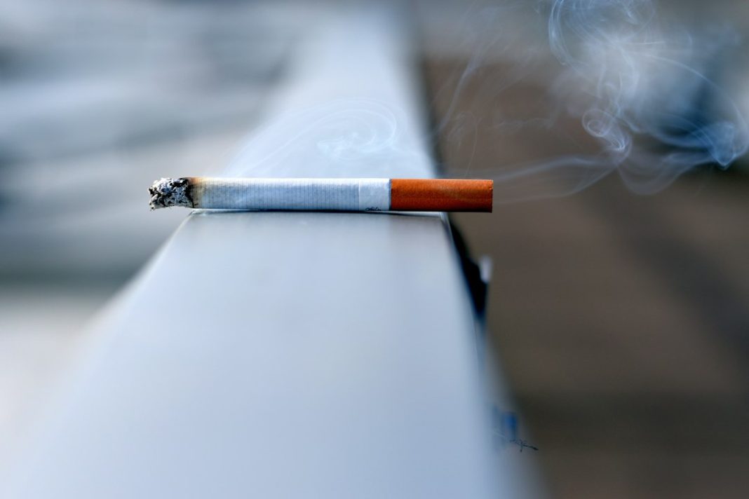 A cigarette on a plain background, illustrating tobacco exposure. Photo by Andres Siimon on Unsplash.