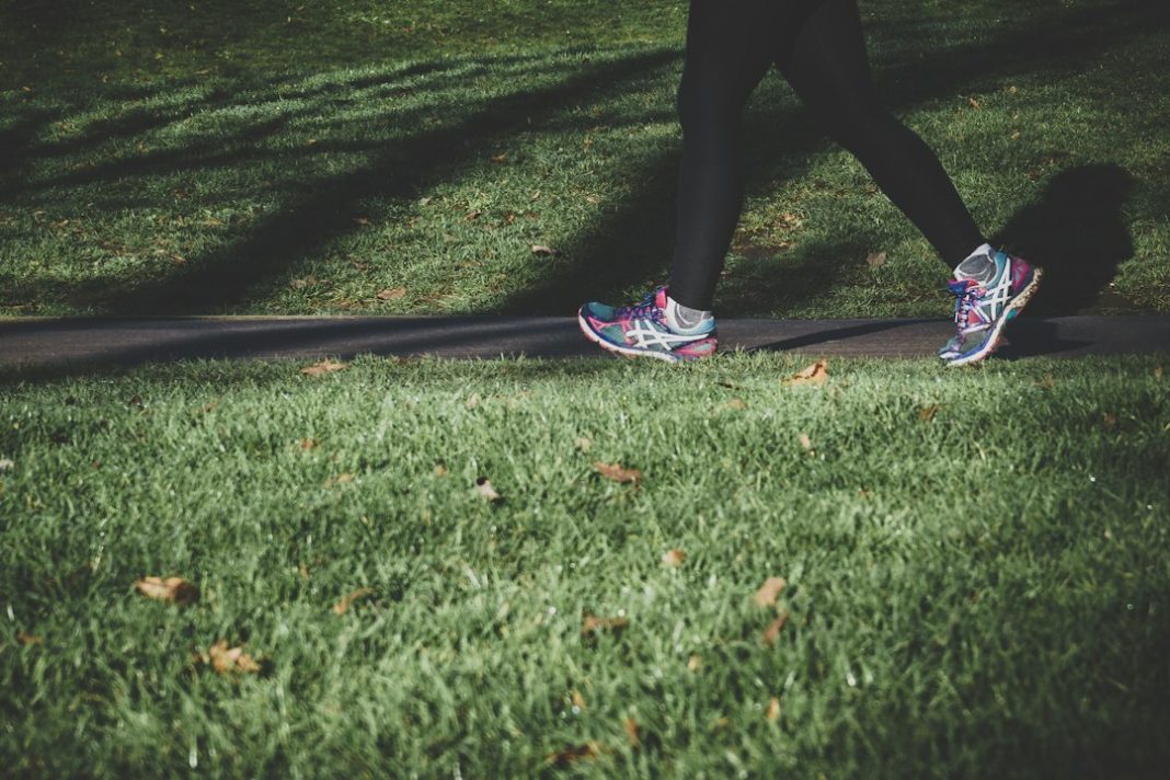Adult running on a park path as part of a weekly physical activity plan